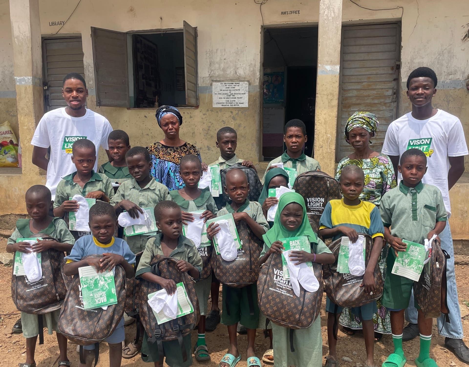Pupils holding their new school bags with Vision Light volunteers